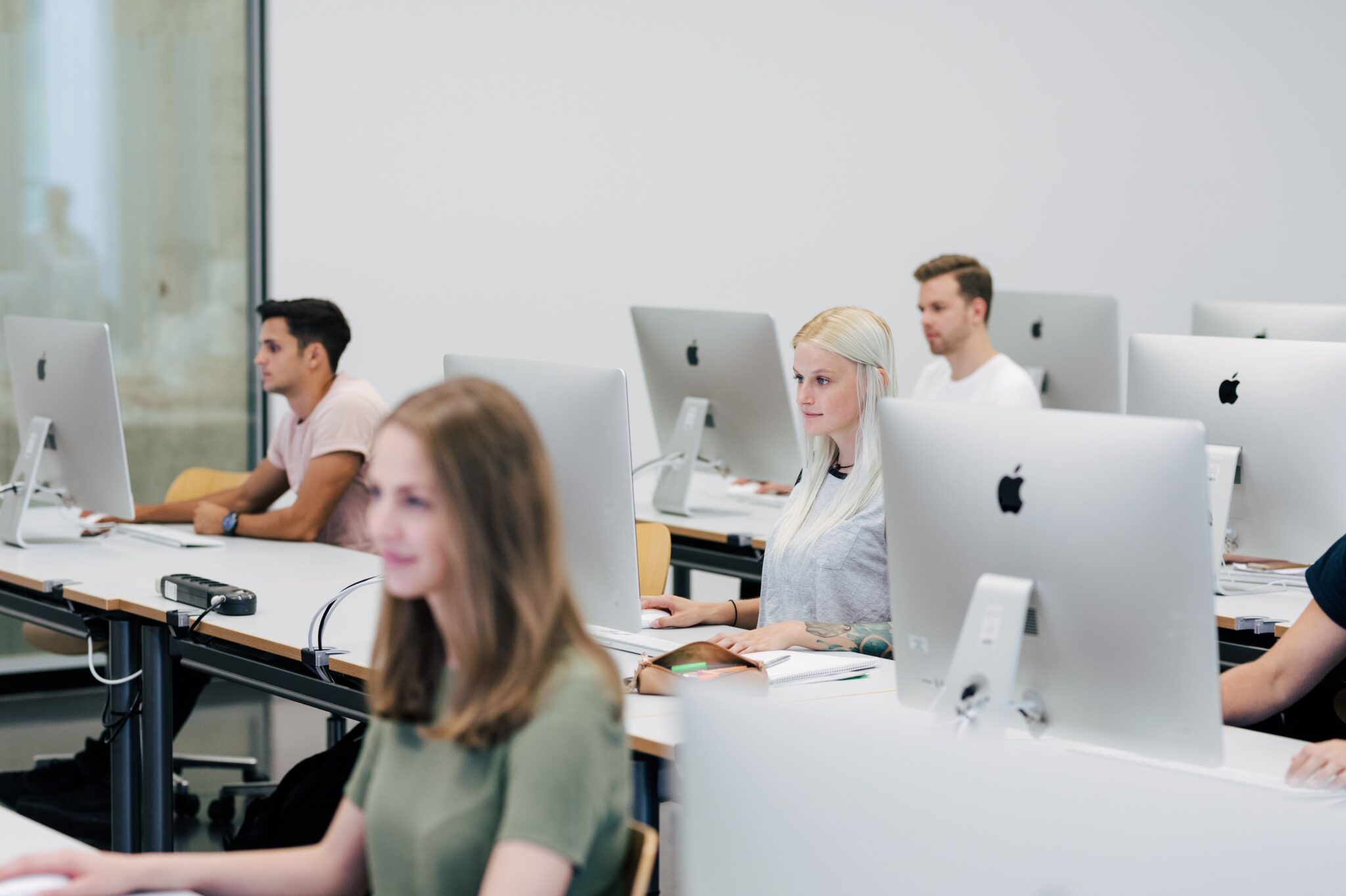 Menschen sitzen an einem Tisch und arbeiten an einem Laptop.